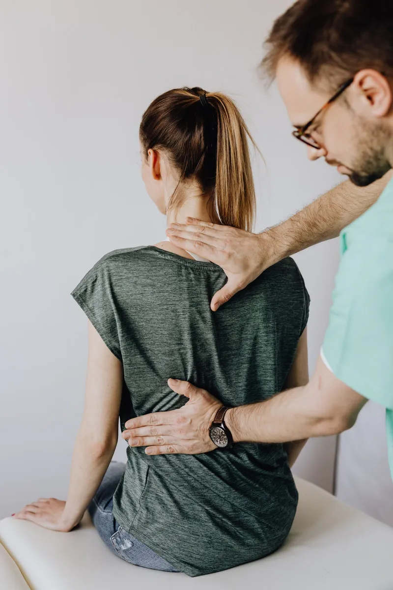 Klinikte uzman, hastanın sırtını ve omurga duruşunu elleriyle değerlendiriyor